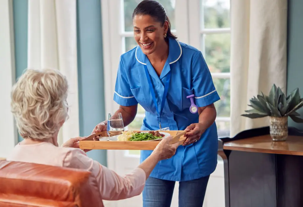 A woman serving food to an older person.